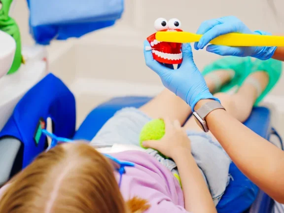 Chirurfien-dentiste rassurant et expliquant le brossage de dent à une enfant