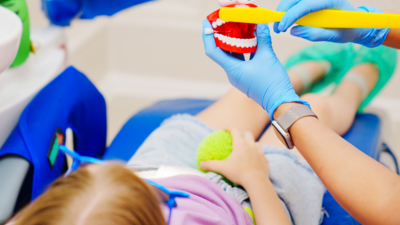 Chirurfien-dentiste rassurant et expliquant le brossage de dent à une enfant